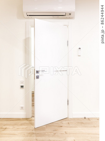 White opened door in modern home with air conditioner and wooden floor White opened door in modern home with air conditioner and wooden floor 86244944
