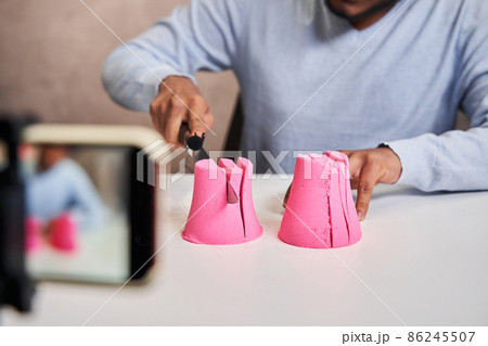 Blogger guy holding knife and preparing destroying pink molds from kinetic sand Blogger guy holding knife and preparing destroying pink molds from kinetic sand 86245507