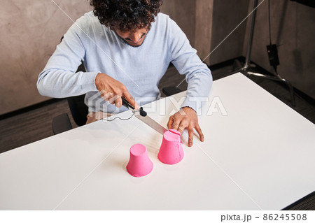 Multiracial man with curly hair cutting molds from kinetic sand Multiracial man with curly hair cutting molds from kinetic sand 86245508