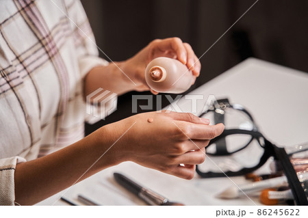 Blogger woman putting drop of her tone cream at hand while broadcasting make up tutorial Blogger woman putting drop of her tone cream at hand while broadcasting make up tutorial 86245622