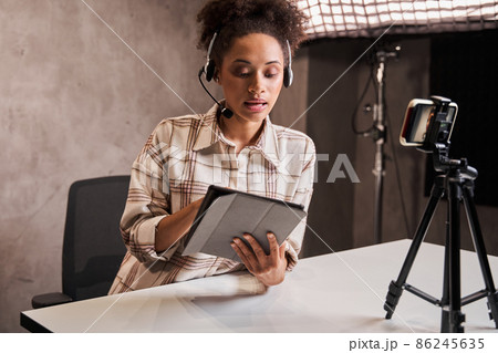 Young multiracial woman sitting at the studio and looking at the tablet 86245635