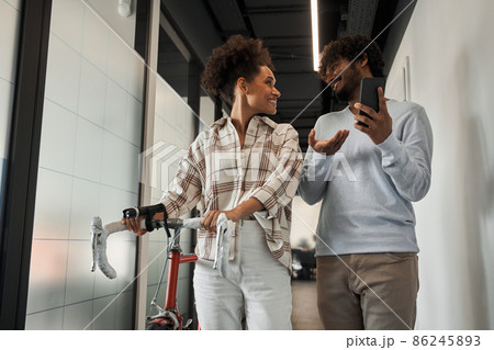 Multiracial colleagues going through the hall together with bicycle Multiracial colleagues going through the hall together with bicycle 86245893