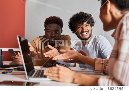 Smiling diverse coworkers sitting at desk in the separate room and making notes 86245964