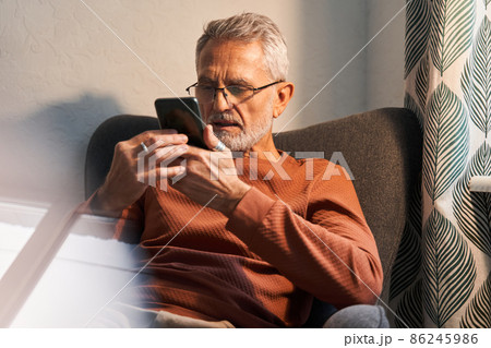 Smiling retirement man at home using modern smartphone 86245986
