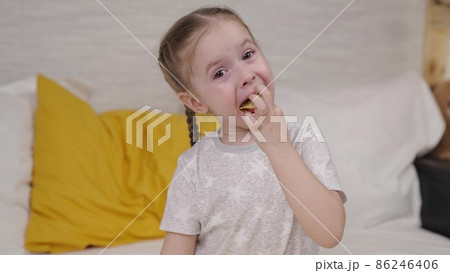 little girl eating potato chips while sitting on the bed, enjoying taste of crisp at home, useless food with spices, seasoned food snack small child, happiness in children's variety goodies vegetable little girl eating potato chips while sitting on the bed, enjoying taste of crisp at home, useless food with spices, seasoned food snack small child, happiness in children's variety goodies vegetable 86246406