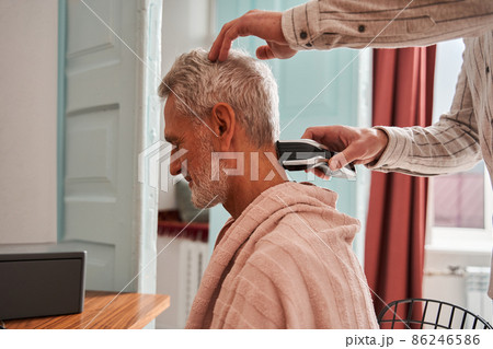 Son cutting his father's back of the head with special trimmer Son cutting his father's back of the head with special trimmer 86246586