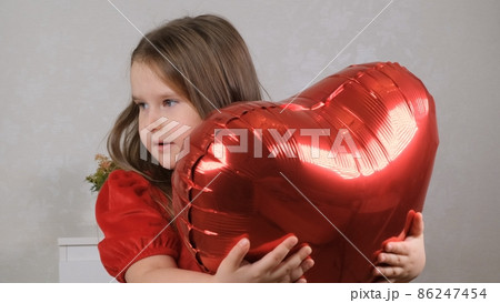 Pretty cute girl holding heart shaped crane balloons on valentines day. 86247454