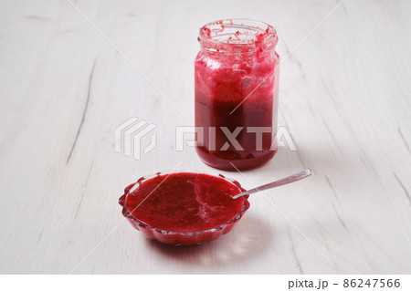 Jar and saucer with cherry jam on white wooden background 86247566