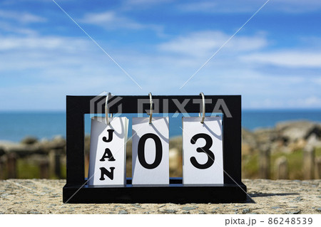 Jan 02 calendar date text on wooden frame with blurred background of ocean 86248539