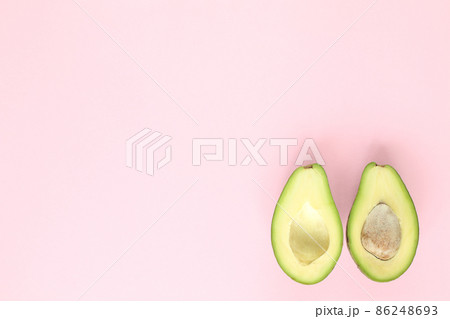 Two halfs of avocado with and without seed on pink background. Top view. 86248693