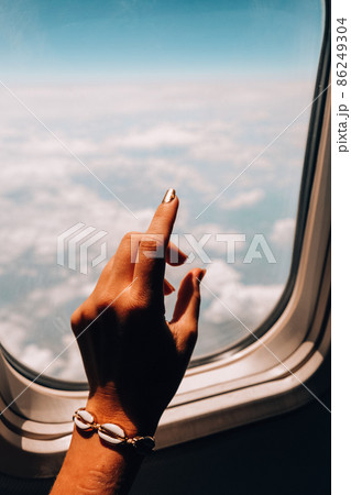 Female hand View from the window of the plane. Airplane, Aircraft. Traveling by air. Vacation travel concept Airplane Window View Above the Clouds Amazing golden fluffy clouds moving softly 86249304