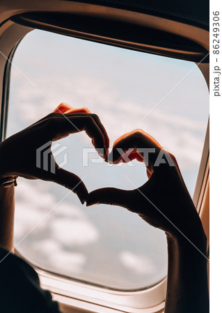 Female hand in heart shape View from the window of the plane. Airplane, Aircraft. Traveling by air. Vacation love travel concept Airplane Window View Above the Clouds Amazing golden fluffy clouds 86249306