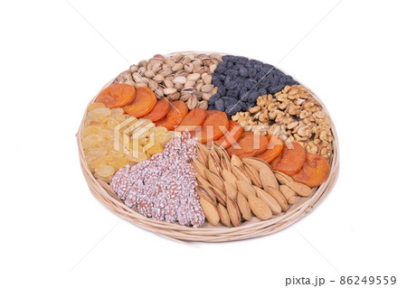 assorted dried fruits and nuts are laid out on a dish of wicker rods assorted dried fruits and nuts are laid out on a dish of wicker rods 86249559