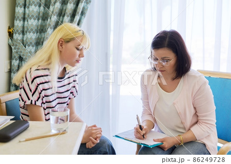 Woman teacher, therapist, social worker talking to teenage student in the office. 86249728