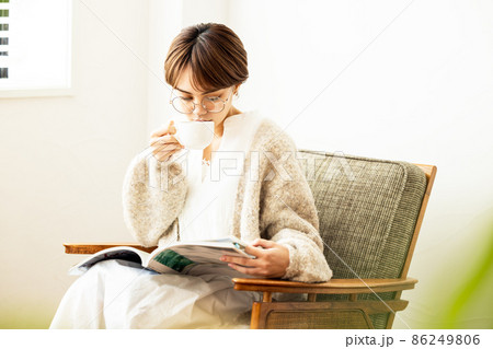 雑誌を見ながらコーヒーを飲む女性 86249806