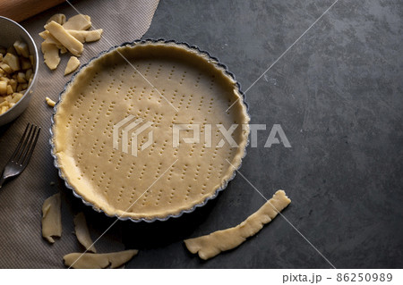 Homemade pie crust in pie plate. Cooking apple pie, dark background. Copy space Homemade pie crust in pie plate. Cooking apple pie, dark background. Copy space 86250989