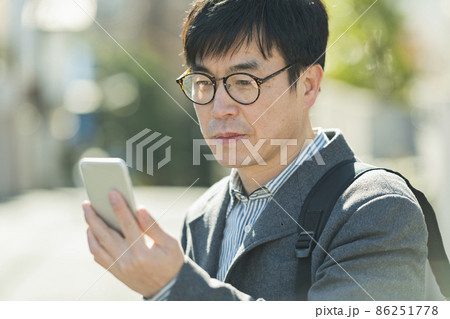 散歩中に携帯電話を見る男性 散歩中に携帯電話を見る男性 86251778