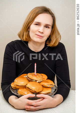 a woman makes a wish and blows out a candle on a hamburger cake. original cake.  86252630