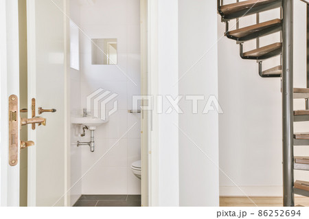 opened white door of a toilet room next to the stairs of a house 86252694