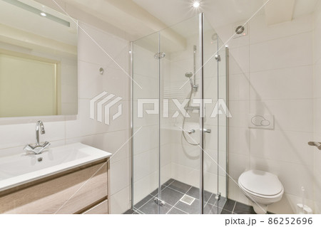 Interior of a modern white bathroom with shower cabinet,toilet,sink,mirror 86252696