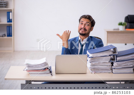 Young male employee and too much work in the office 86253103