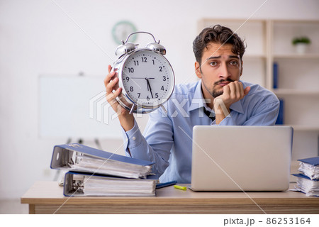 Young male employee in time management concept Young male employee in time management concept 86253164