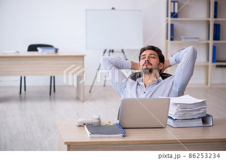 Young male employee and too much work in the office Young male employee and too much work in the office 86253234