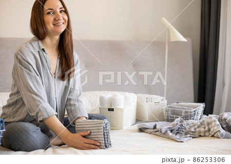 Spring cleaning of closet. Vertical tidying up storage. Neatly folded clothes in the metal white baskets for wardrobe. Nordic style. 86253306