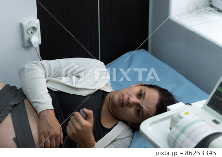 Pregnant Woman On Hospital Couch During Medical Control Cardiotocography. Gynecologist Doctor Hands Turn On Adjust CTG Device Clinic Consultant. Examine Expectant Belly Baby Mother Healthcare Check Up Pregnant Woman On Hospital Couch During Medical Control Cardiotocography. Gynecologist Doctor Hands Turn On Adjust CTG Device Clinic Consultant. Examine Expectant Belly Baby Mother Healthcare Check Up 86253345