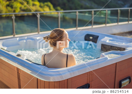 Portrait of young carefree happy smiling woman relaxing at hot tub during enjoying happy traveling moment vacation life against the background of green big mountains Portrait of young carefree happy smiling woman relaxing at hot tub during enjoying happy traveling moment vacation life against the background of green big mountains 86254514