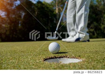 Golfer putting ball on the green golf, lens flare on sun set evening time. Golfer action to win after long putting golf ball in to the hole 86256823