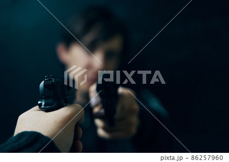 Close-up of man's hand with gun pointed at criminal with revolver. Shootout of two thieves or murderers. Firearms for attack or defense. Close-up of man's hand with gun pointed at criminal with revolver. Shootout of two thieves or murderers. Firearms for attack or defense. 86257960