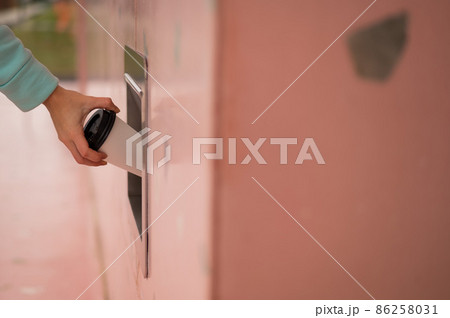 A woman throws a cup of coffee into a garbage manhole in the wall of a cafe. A woman throws a cup of coffee into a garbage manhole in the wall of a cafe. 86258031