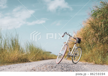 Vintage bicycle on country road and field with blue sky and white cloud abstract background. 86259394