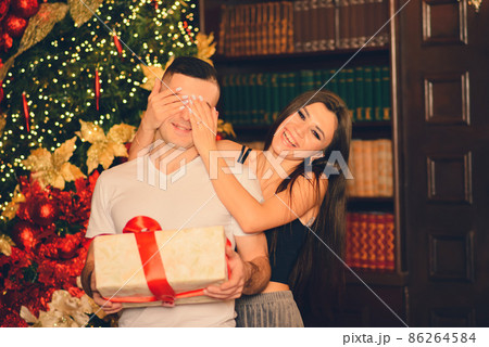 Boyfriend looks to his christmas gift while his girlfriend give him a kiss Boyfriend looks to his christmas gift while his girlfriend give him a kiss 86264584