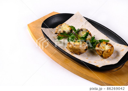 Baked stuffed mushrooms with mushrooms, cheese and herbs, on a wooden board on a white isolated background 86269042