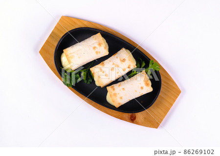 Grilled lavash rolls with suluguni cheese, picnic lunch, appetizer, delicious dish in a frying pan on a white isolated background 86269102