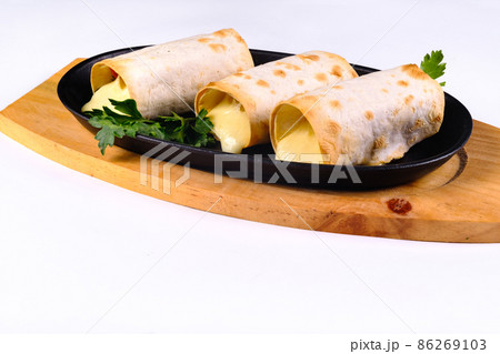 Grilled lavash rolls with suluguni cheese, picnic lunch, appetizer, delicious dish in a frying pan on a white isolated background 86269103