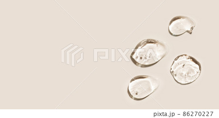 Transparent hyaluronic acid gel drops on a beige background. 86270227