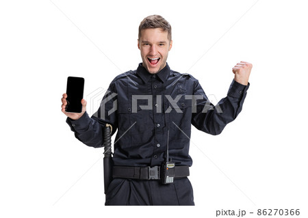 Portrait of young man, policeman officer wearing black uniform using phone isolated on white background. Concept of job, caree, law and order. 86270366