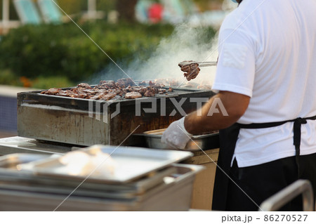 Metal construction for frying meat in nature, male chef do grill 86270527