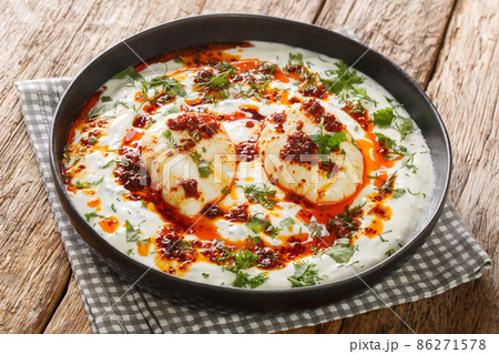 Cilbir is a Turkish eggs containing garlicky yogurt, poached eggs, and spiced melted butter in the plate. Horizontal Cilbir is a Turkish eggs containing garlicky yogurt, poached eggs, and spiced melted butter in the plate. Horizontal 86271578