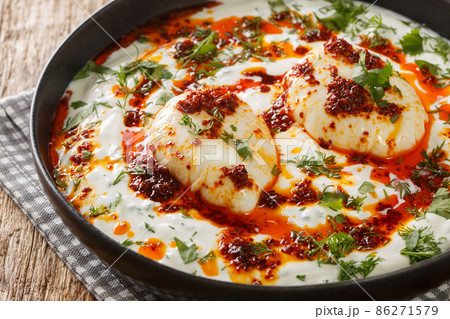 Turkish eggs or Cilbir are made with Greek yoghurt combined with fresh herbs and garlic closeup in the plate. Horizontal Turkish eggs or Cilbir are made with Greek yoghurt combined with fresh herbs and garlic closeup in the plate. Horizontal 86271579