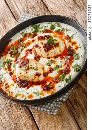 Turkish dish of poached eggs with yogurt closeup in the plate. Vertical Turkish dish of poached eggs with yogurt closeup in the plate. Vertical 86271582