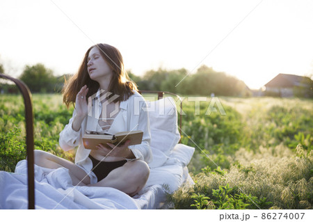 girl reading a book in bed among the fields at sunset girl reading a book in bed among the fields at sunset 86274007