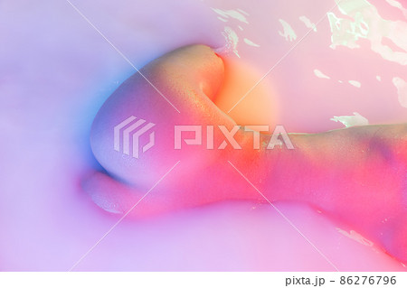 Closeup female hips, bottocks in the milk bath with soft pink neon glow. Beauty, fashion, style, bodycare, spa concept. Closeup female hips, bottocks in the milk bath with soft pink neon glow. Beauty, fashion, style, bodycare, spa concept. 86276796
