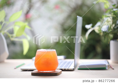 Carrot juice and laptop on wooden desk  86277266
