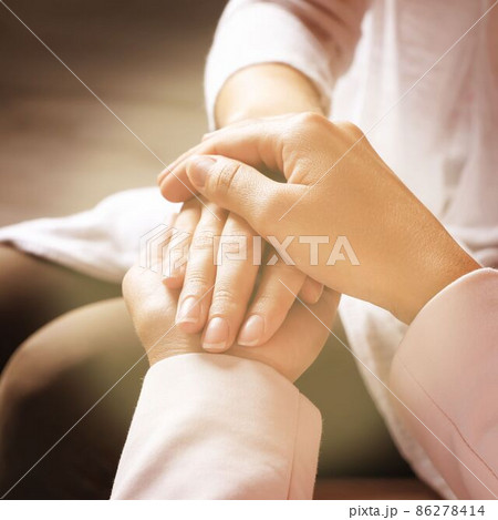 Volunteer holding hands with woman in sunlit room, closeup Volunteer holding hands with woman in sunlit room, closeup 86278414