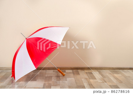 Beautiful colorful umbrella near beige wall. Space for text 86278616