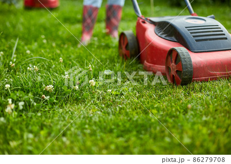unrecognizable Woman mows the lawn with a lawn mower grass at home garden, gardener woman working 86279708